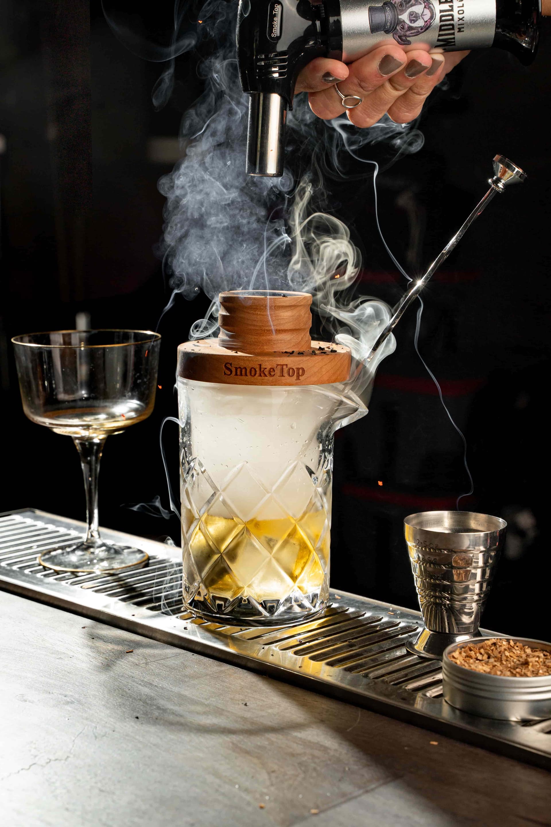 Bartender using SmokeTop on a crystal mixing glass at a professional bar