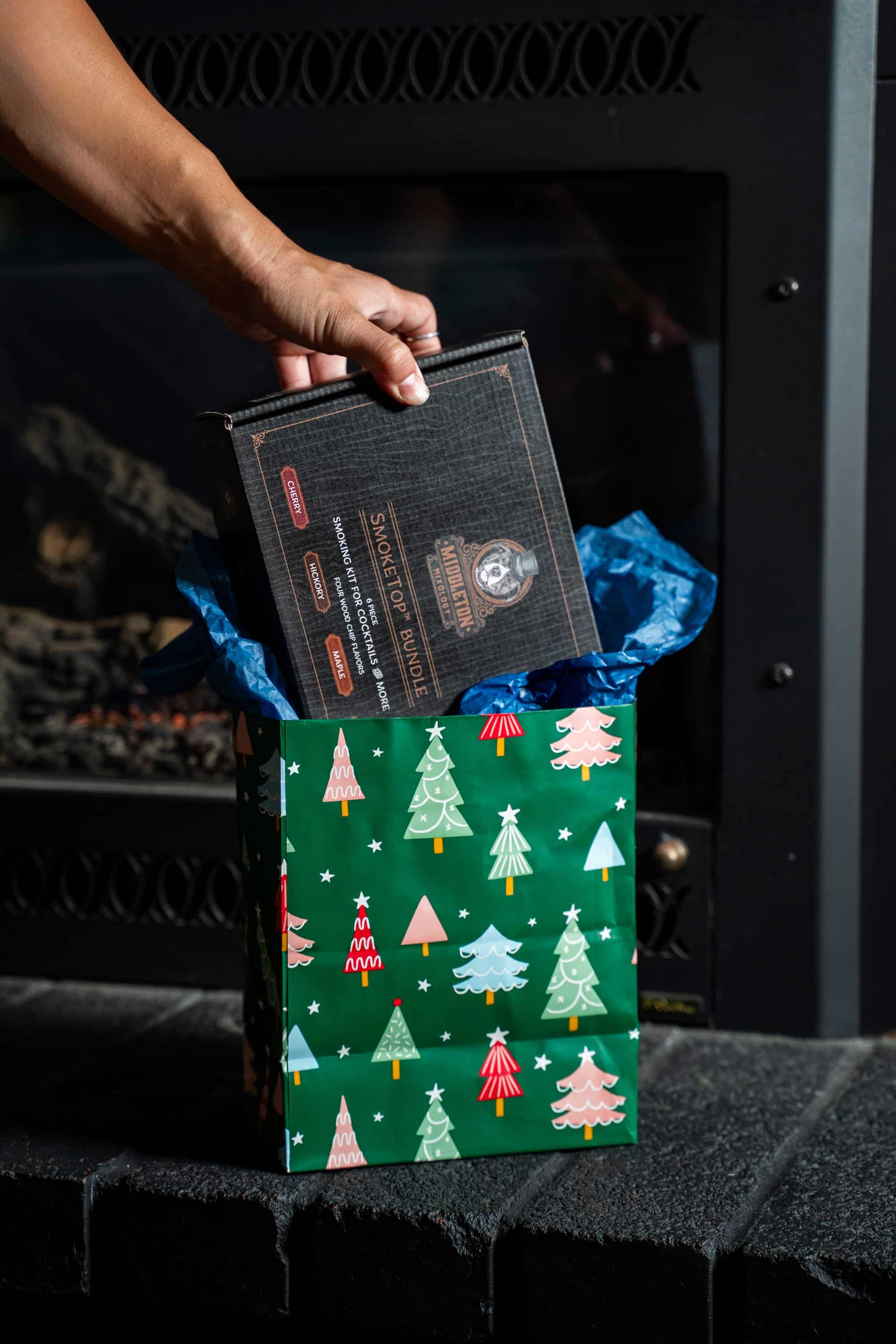 SmokeTop cocktail smoker bundle being pulled from a holiday gift bag by a fireplace